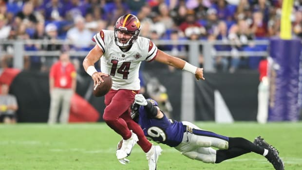 Washington Commanders quarterback Sam Howell (14) scrambles away from a diving Baltimore Ravens safety Ar'Darius Washington (29) during the second half at M&T Bank Stadium.